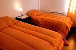 two beds with orange covers in a room at FIN DEL MUNDO - EDIFICIO AUSTRALIS in Ushuaia