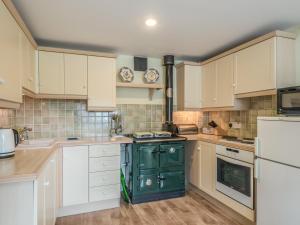 uma cozinha com armários brancos e um fogão verde em Hope Hall Barn em Bromlow
