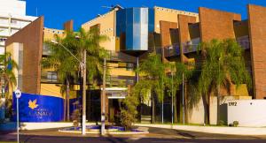 a building with palm trees in front of it at Hotel Canada in Ribeirão Preto