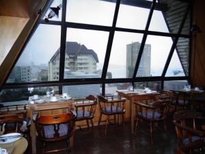 a restaurant with tables and chairs and a large window at Hotel Antupiren in Puerto Montt