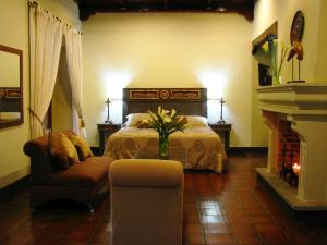 a bedroom with a bed and a chair and a fireplace at Casa Santa Rosa Hotel Boutique in Antigua Guatemala