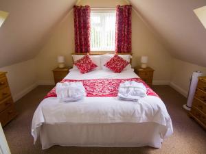 a bedroom with a large bed with red curtains at The Lodge at Orchard House in Norwich