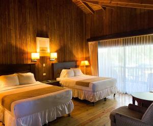a hotel room with two beds and a window at La Ensenada Beach Resort in Tela