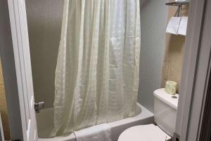 a bathroom with a shower curtain and a toilet at Super 8 by Wyndham Newport News in Newport News