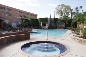 a swimming pool with a fountain in a courtyard at Ramada by Wyndham Viscount Suites Tucson East in Tucson