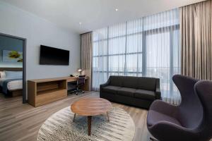 a living room with a couch and a television and a bed at Wingate by Wyndham Long Island City in Queens