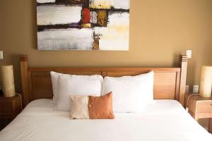 a bed with white pillows and a painting on the wall at Acanto Hotel Playa del Carmen, Trademark Collection by Wyndham in Playa del Carmen