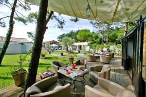a patio with a bunch of chairs and tables at Hôtel Restaurant & Spa Plaisir in Le Bois-Plage-en-Ré