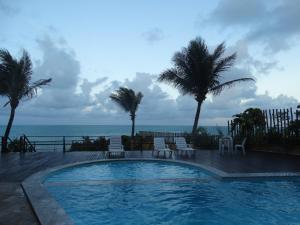 a swimming pool with palm trees and the ocean at Atlantico Flat Ap. 107 in Natal