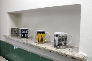 quatre tasses à café assises sur une étagère dans une cuisine dans l'établissement Love and More House, à Imola