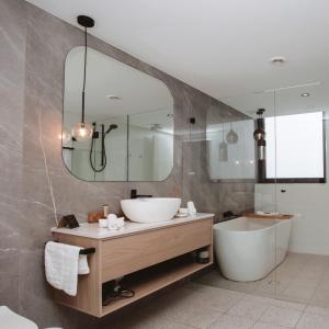 a bathroom with a sink and a tub and a mirror at Pasadena Sydney in Church Point