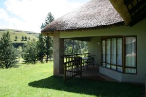 a house with a grass roof and a patio at Fairways Holiday Accommodation in Drakensberg Garden