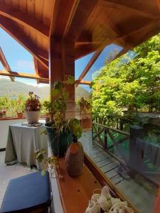 un balcón con macetas y una mesa en el techo en Las Rosas Alojamiento Turistico en Villa La Angostura