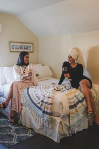 two women sitting on a bed with glasses of wine at La Villa de Adelina in Ensenada +69 photos