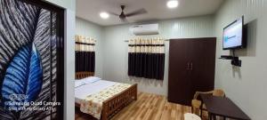 Schlafzimmer mit einem Bett und einem Flachbild-TV in der Unterkunft Vidhara Rooms in Thiruvananthapuram