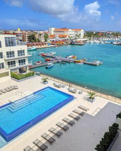 a large swimming pool next to a body of water at Luxury condo with infinity pool & ocean view in Oranjestad