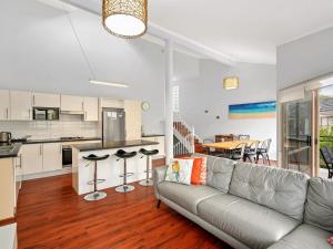 a living room with a couch and a kitchen at Spacious House with Balcony & Pool, Walks to Beach in Terrigal