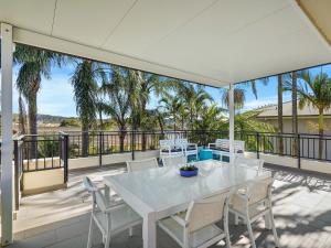 a white table and chairs on a balcony with palm trees at Spacious Beachside Townhouse with Large Balcony in Terrigal