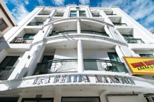 un grand bâtiment blanc avec un panneau sur celui-ci dans l'établissement RedDoorz at Samat Mandaluyong, à Manille