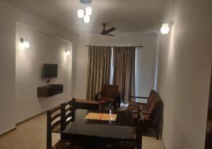 uma sala de estar com uma mesa e cadeiras e uma ventoinha de tecto em Areia De Goa - Sunset By Leela Homes em Arpora