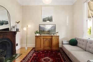 een woonkamer met een bank en een tv bij Central Geelong West Cottage in Geelong West