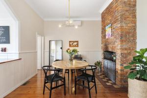 een eetkamer met een tafel en stoelen en een bakstenen muur bij Central Geelong West Cottage in Geelong West