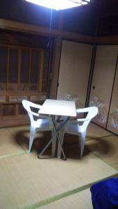 uma mesa branca e duas cadeiras num quarto em raibrasil guest house em Sanuki