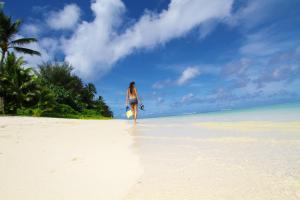 a woman walking on a beach with a frisbee at Moana Sands Beachfront Hotel in Rarotonga
