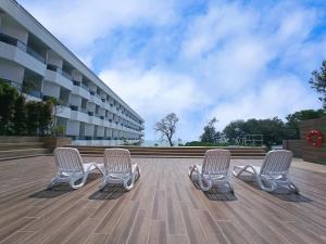 3 sillas sentadas en una terraza frente a un edificio en Pacific Regency Beach Resort, Port Dickson, en Port Dickson