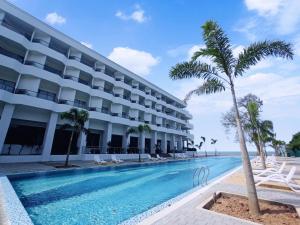 a hotel with a swimming pool and palm trees at Pacific Regency Beach Resort, Port Dickson in Port Dickson