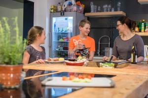 a group of people standing around a kitchen counter with food at Oberstdorf Hostel in Oberstdorf
