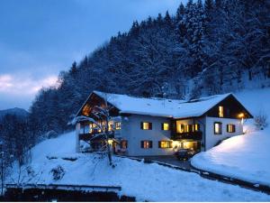 a house covered in snow at night with lights at Landhotel Sonnleiten in Bad Reichenhall