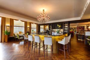 a bar in a restaurant with white chairs and a chandelier at Hotel Chemnitzer Hof in Chemnitz