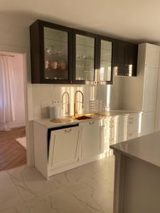 una cocina con armarios blancos y fregadero en Apartament Złoty, en Zblewo