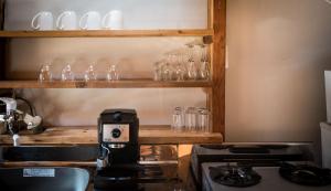 a kitchen with a coffee maker and glasses on a shelf at Yukiita Lodge in Hakuba