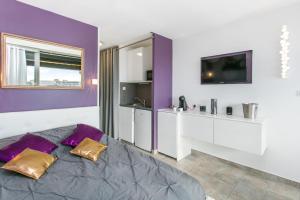 um quarto roxo e branco com uma cama e uma televisão em Village Naturiste R4N - Le Candi Port Venus Panoramic View em Cap d'Agde
