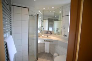 a bathroom with a sink and a shower with a mirror at Landgasthof Hotel Löwen in Wildberg