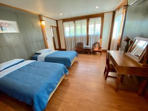 a hotel room with two beds and a desk at ท่ามะโอบูทีคโฮมสเตย์ Tha Ma-O Bouteak Homestay in Lampang