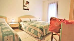 a bedroom with two beds and a chair at Residence Leopardi - Gemini in Bibione +54 photos