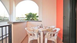 a dining room with a table and white chairs at Residence Leopardi - Gemini in Bibione
