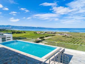 een balkon met uitzicht op de oceaan van een huis met een zwembad bij Aphrodite Beachfront Resort in Ghaziveran