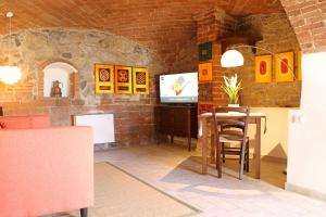 Camera con tavolo e TV in un muro di mattoni di I Voltoni di Corsignano a Siena