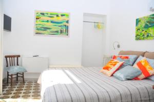 a white bedroom with a bed with colorful pillows at Il Giardino Di Tatiana Rooms & Breakfast in La Maddalena
