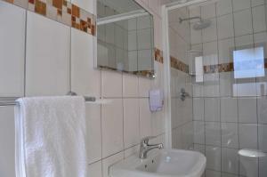 a white bathroom with a sink and a mirror at Timo's guesthouse accommodation in Lüderitz