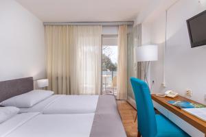 a bedroom with a bed and a desk with a phone at Hotel Zagreb in Crikvenica +18 photos