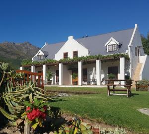 Uma casa branca com um banco à frente. em Chevandeaux 1 - Merlot em Franschhoek