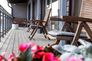 ein Balkon mit Stühlen und Blumen an einem Gebäude in der Unterkunft Hotel Kolumbs in Liepāja