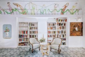 a living room with two chairs and a table and bookshelves at Hotel Terme Oriente - Beach & SPA in Ischia