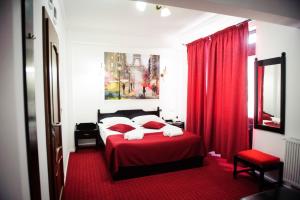 Schlafzimmer mit einem roten Bett und roten Vorhängen in der Unterkunft Pensiunea Maria in Roşiori de Vede