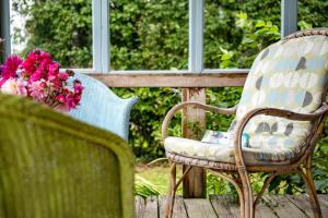 two chairs and a table with flowers on a porch at The HoneyPot in Petham